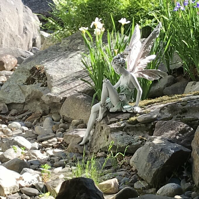 FairyGlo - Une statue de fée assise dans un jardin.