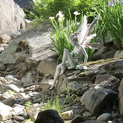 FairyGlo - Une statue de fée assise dans un jardin.