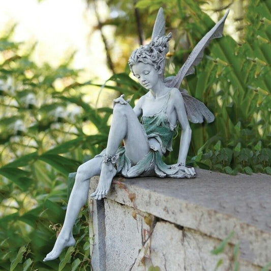 FairyGlo - Une statue de fée assise dans un jardin.
