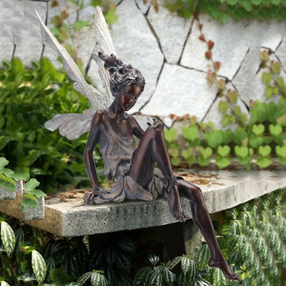 FairyGlo - Une statue de fée assise dans un jardin.