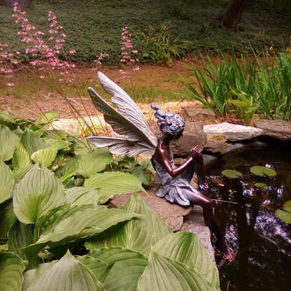 FairyGlo - Une statue de fée assise dans un jardin.